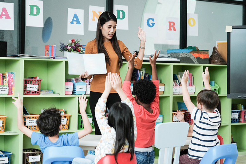 A group of diverse students participating in a a class and engaged with the teacher.