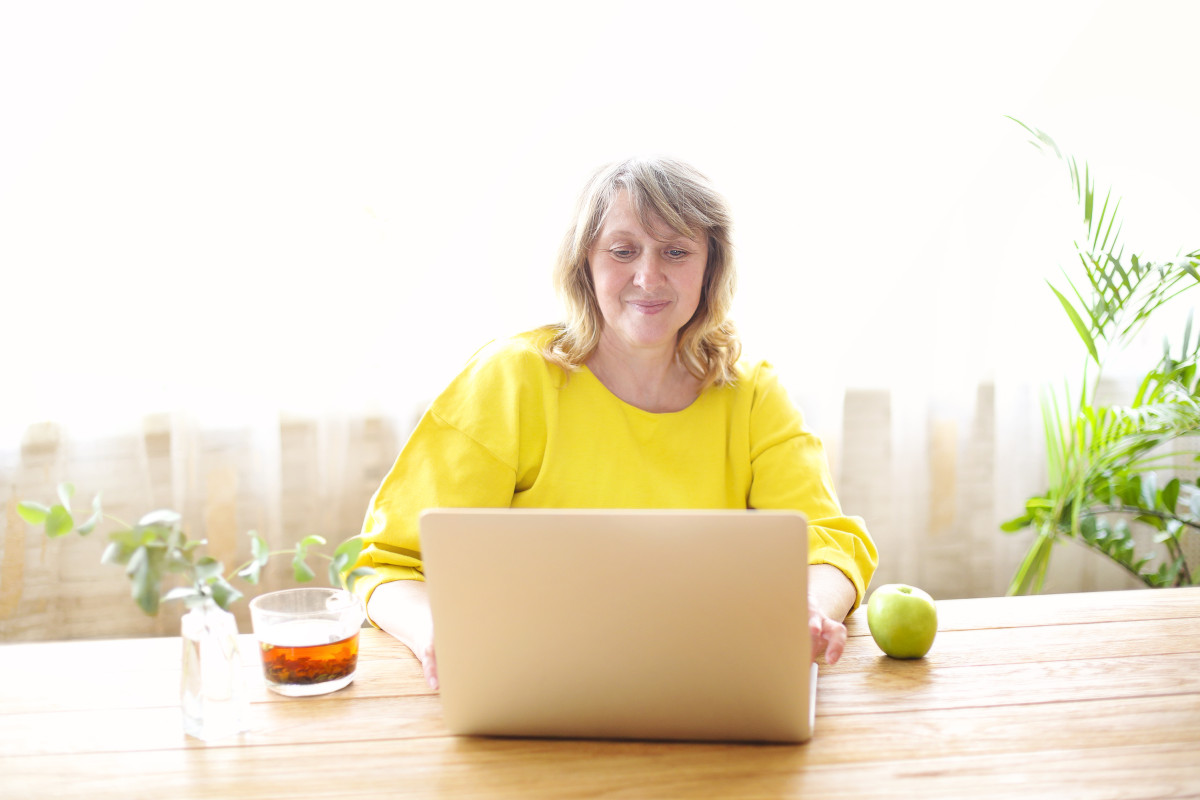 A teacher working on her laptop, engaging in a DominicanCaOnline continuing education course to enhance her classroom skills and meet state certification requirements.