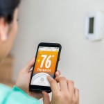 Woman uses smart phone to control smart thermostat.jpg