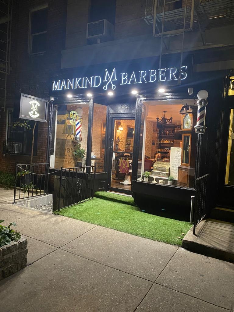 exterior photo of Mankind Barbers NYC at night with illuminated signage